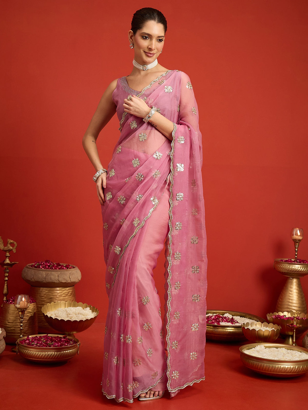 Woman wearing pink chiffon saree with ornamented surface design and pink blouse