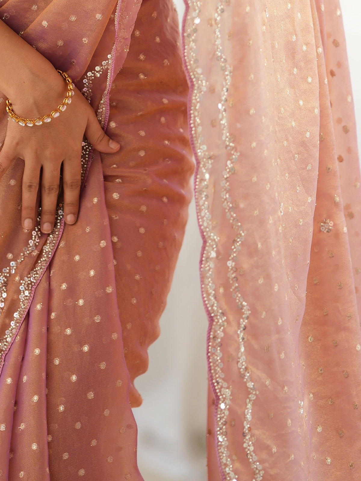 Pallu detail of rose gold georgette saree showing zari butta (metallic motif) work and embellished border