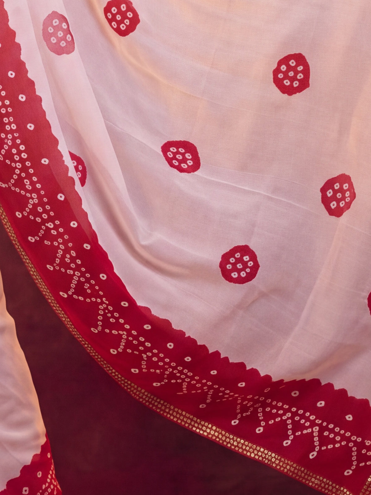Pallu detail of white georgette saree showing bandhani tie-dye dot work and zari border