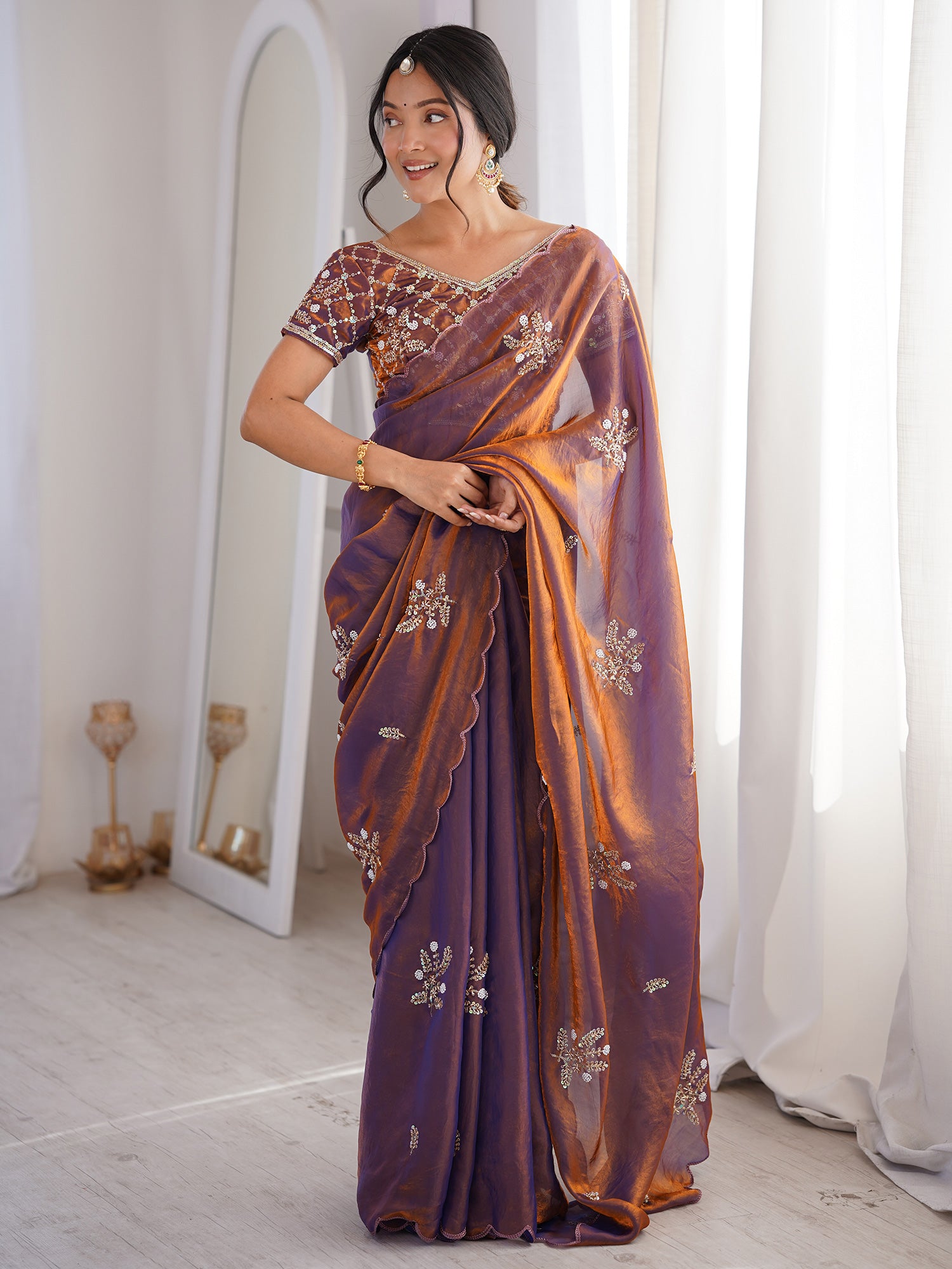 Woman wearing metallic satin saree with ornamented surface design and metallic blouse