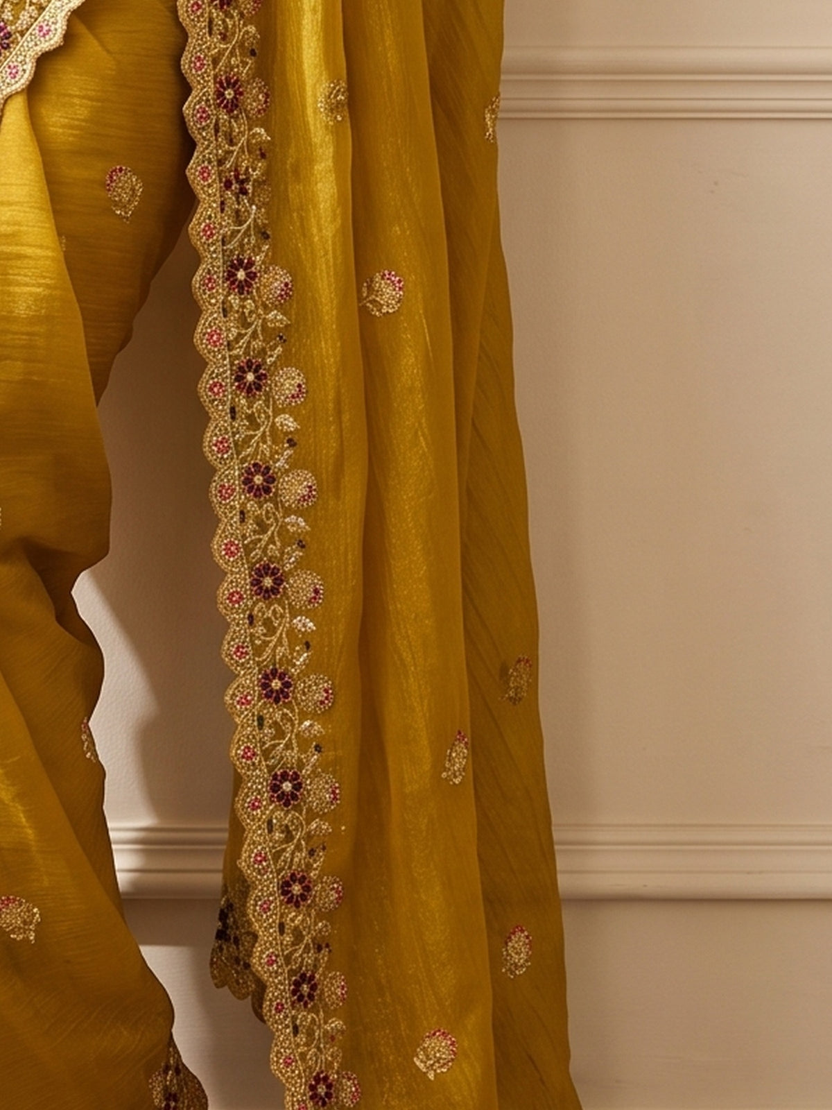 Pallu detail of mustard tissue saree showing ornamented surface design and zari border