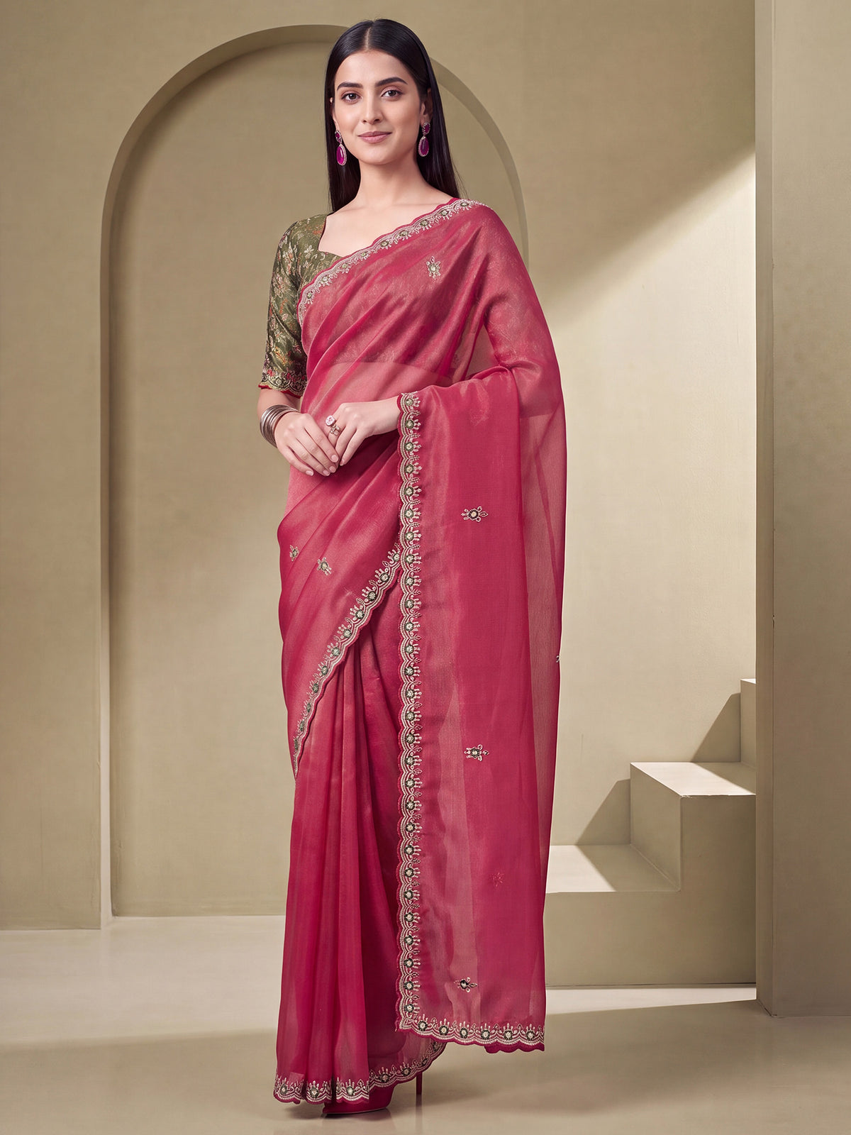 Woman wearing pink tissue saree with ornamented surface design and green blouse
