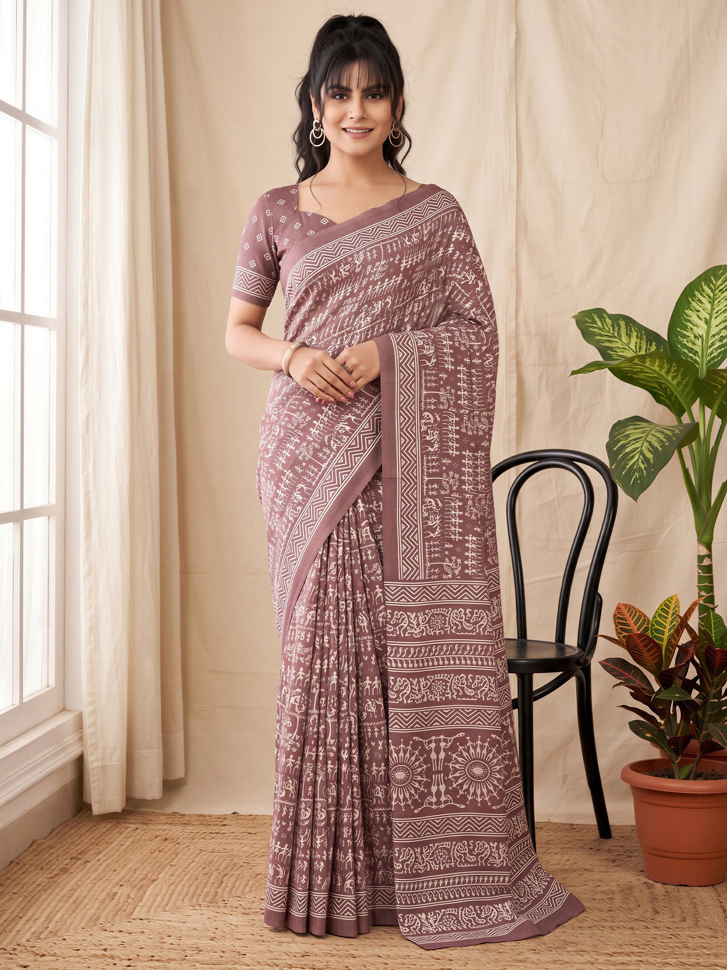 Woman wearing mauve dola silk saree with warli folk-art figures and mauve blouse