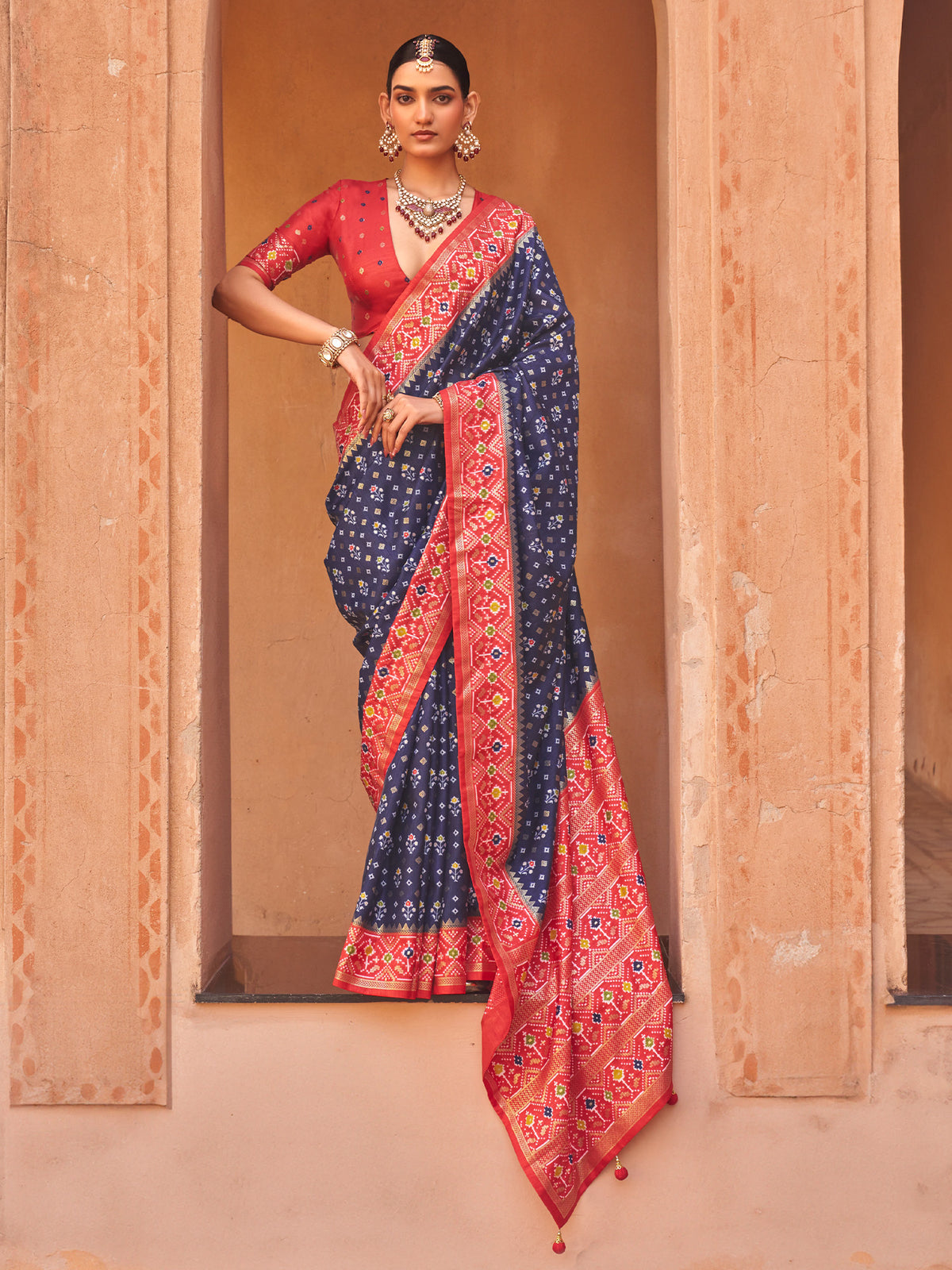 Woman wearing navy blue silk blend saree with ikat resist-dyed pattern and red blouse