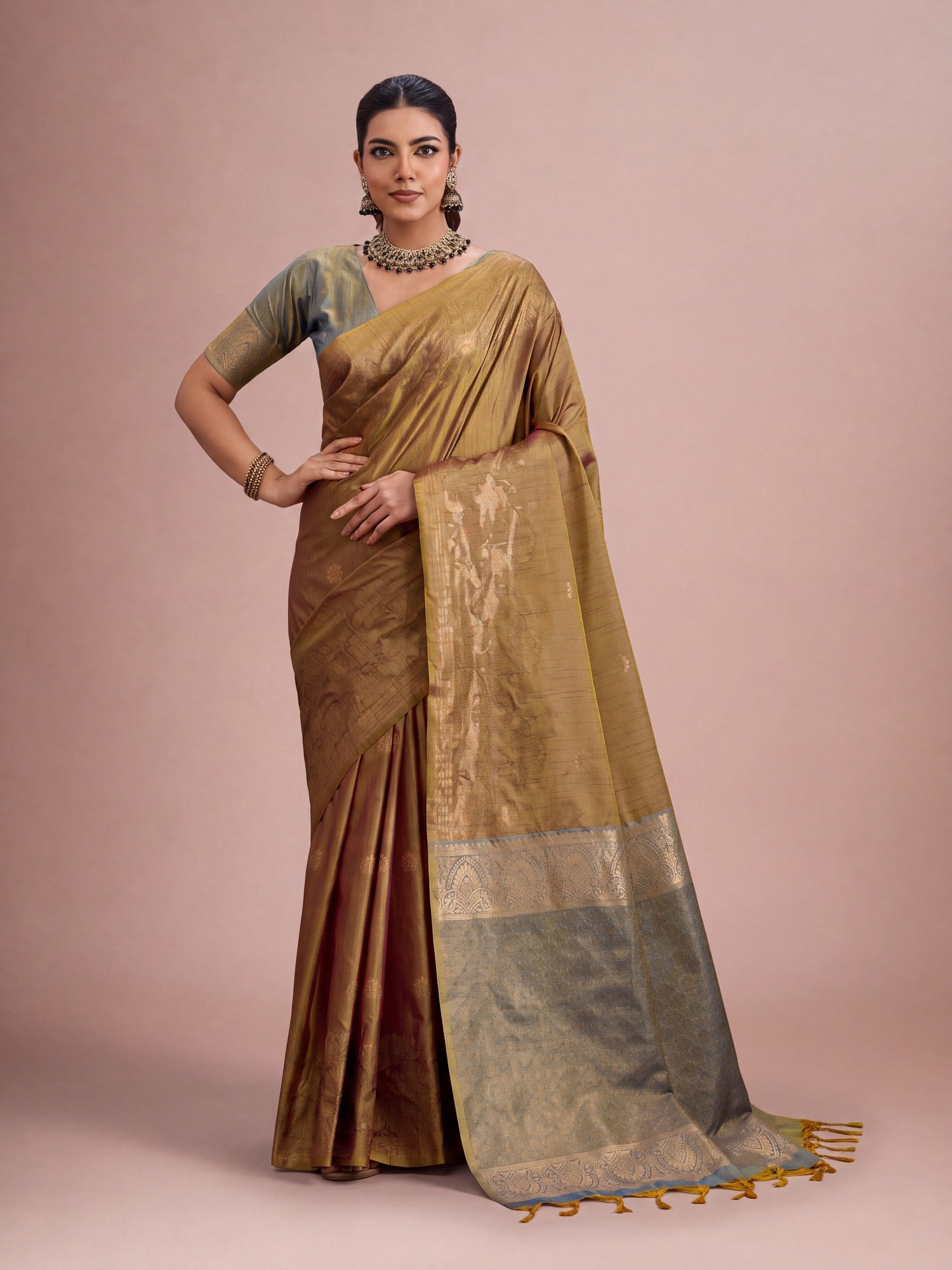 Woman wearing mustard tussar silk saree with traditional indian motif work and blue blouse