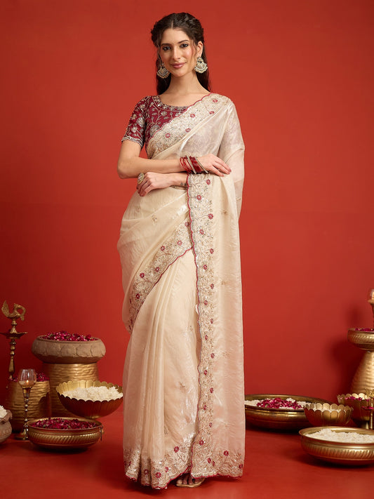 Woman wearing off white satin saree with ornamented surface design and maroon blouse