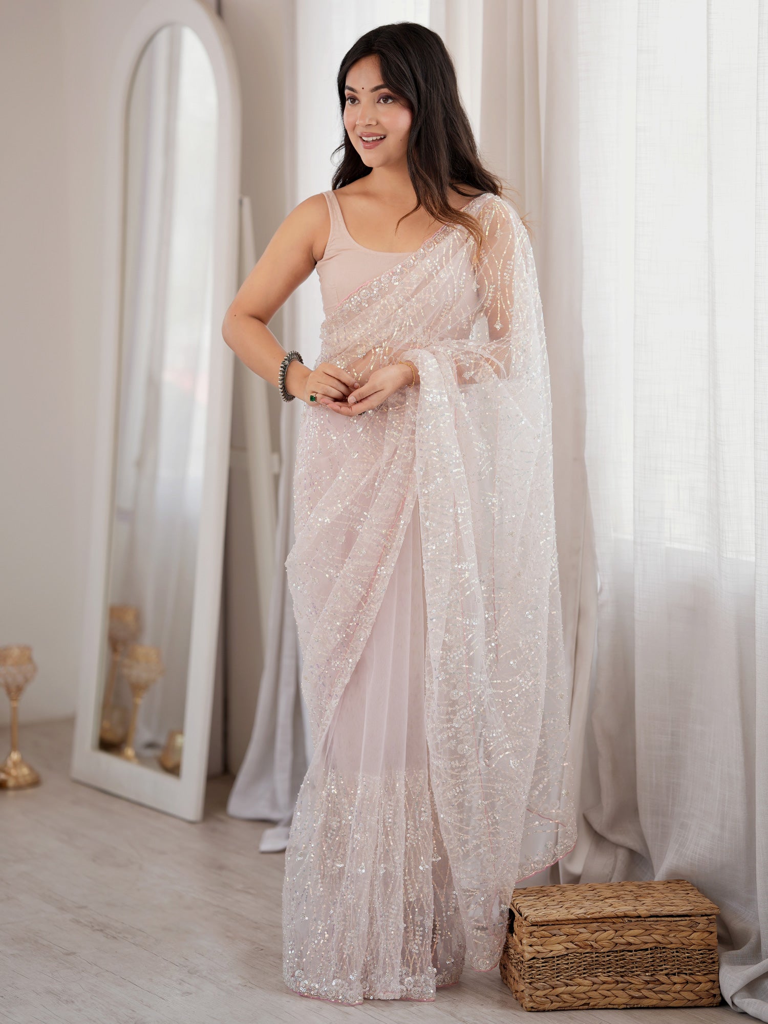 Woman wearing pink net saree with ornamented surface design and pink blouse