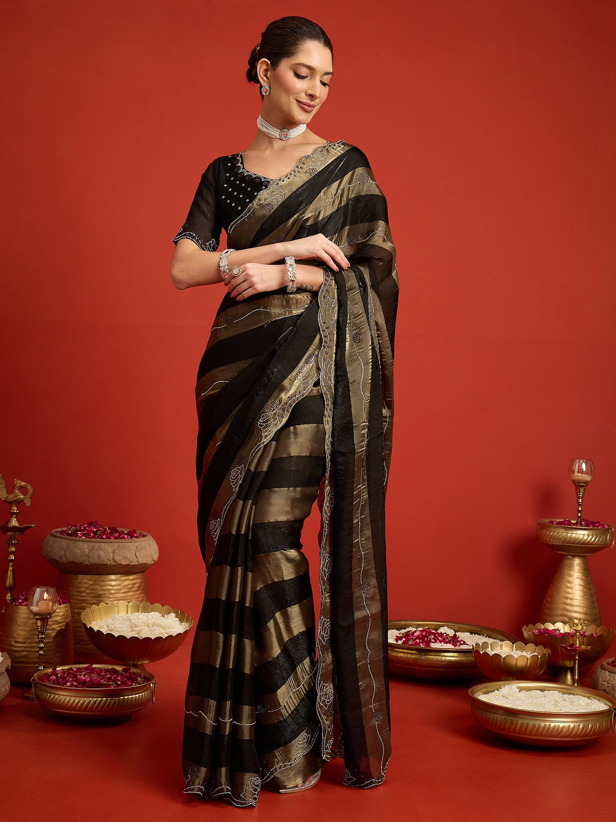 Woman wearing black satin silk saree with ornamented surface design and black blouse