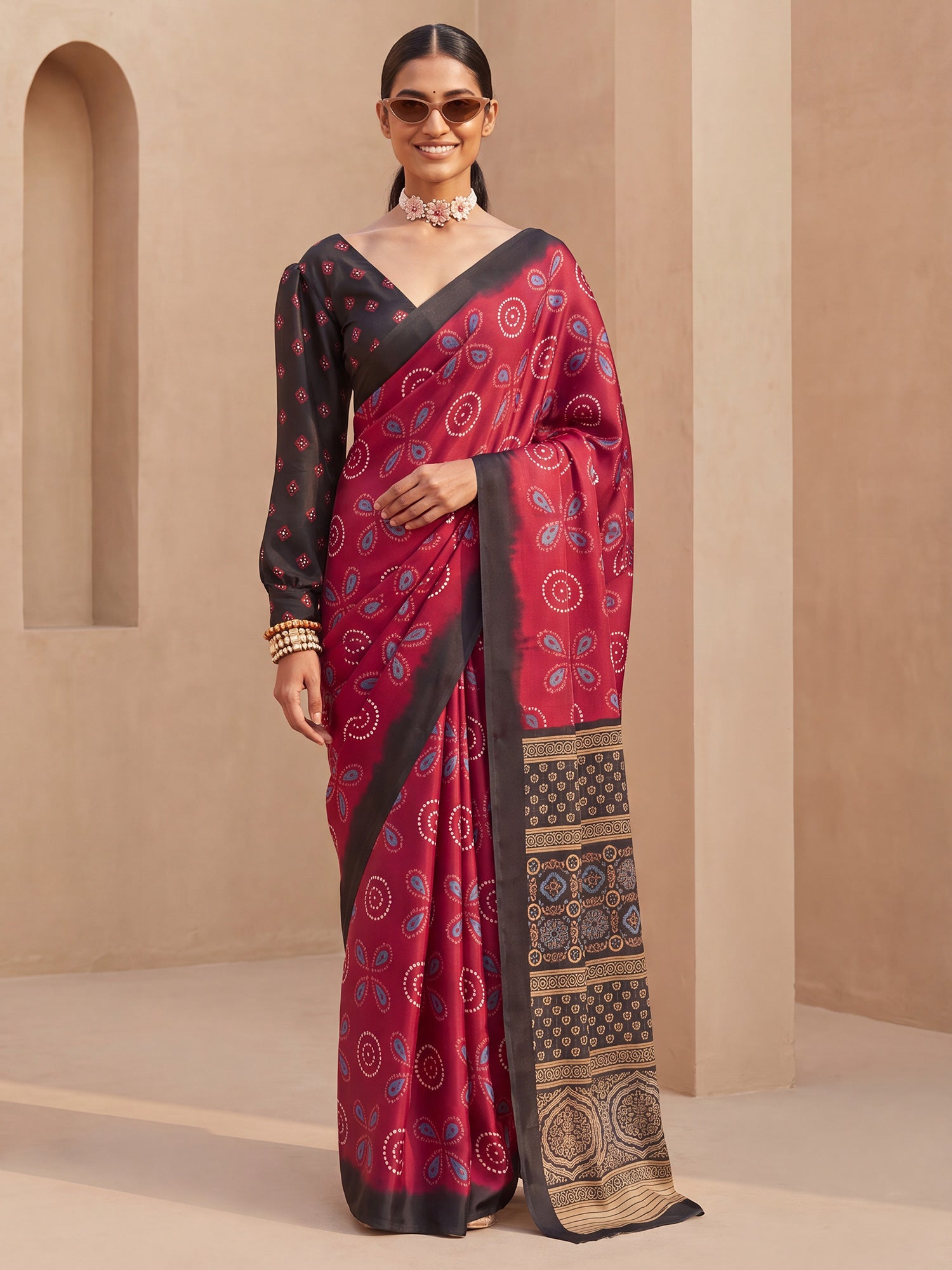 Woman wearing maroon satin saree with traditional indian motif work and black blouse