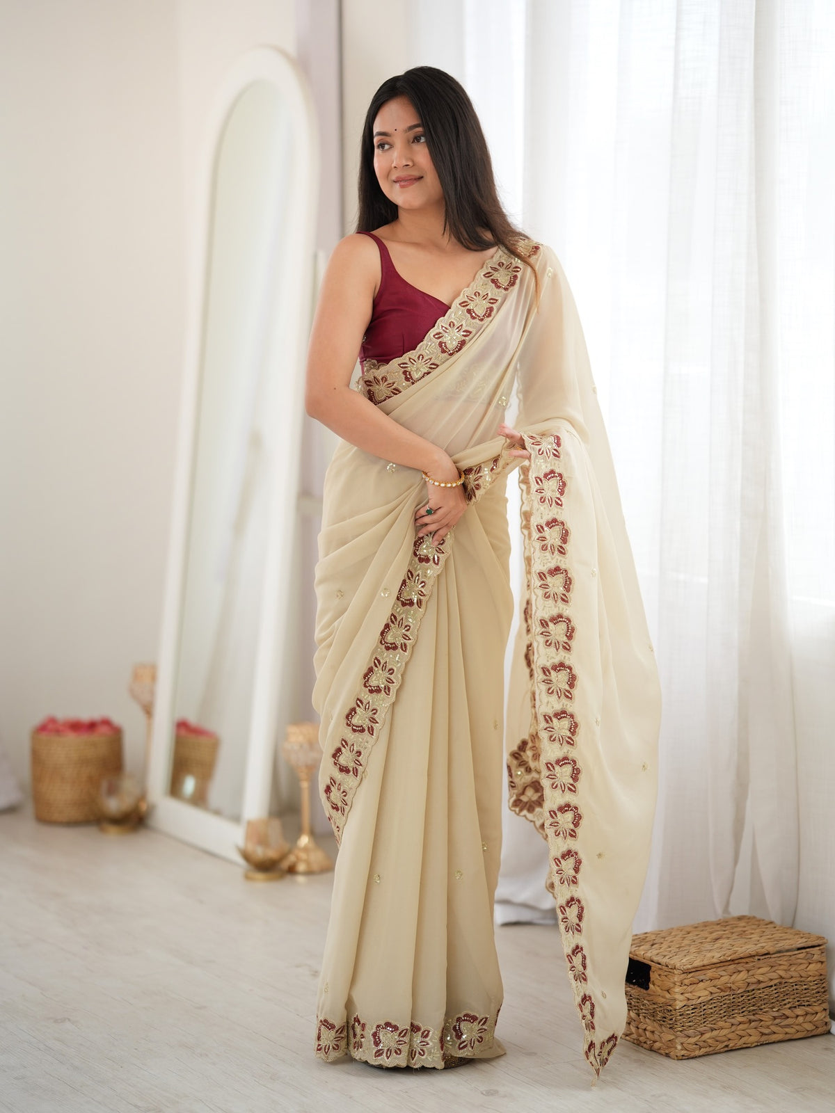 Woman wearing off white georgette saree with ornamented surface design and maroon blouse
