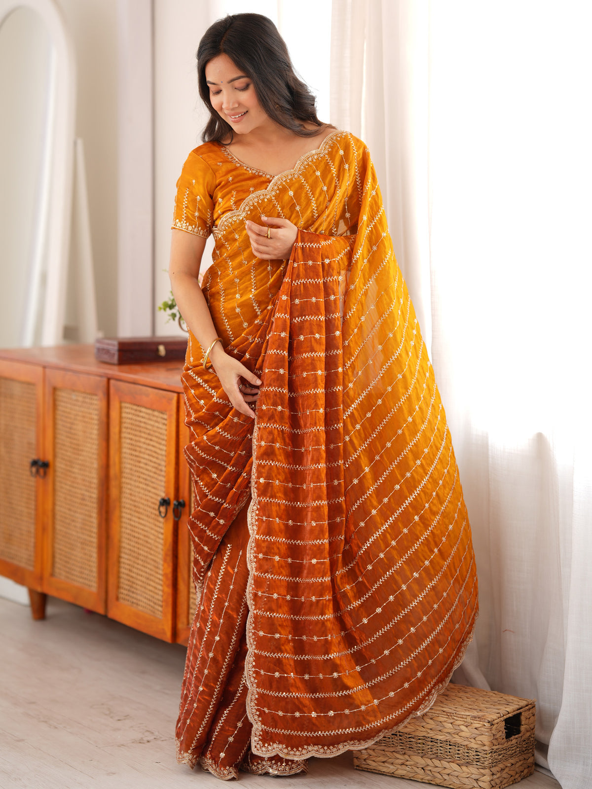 Woman wearing mustard satin saree with striped pattern design and mustard blouse