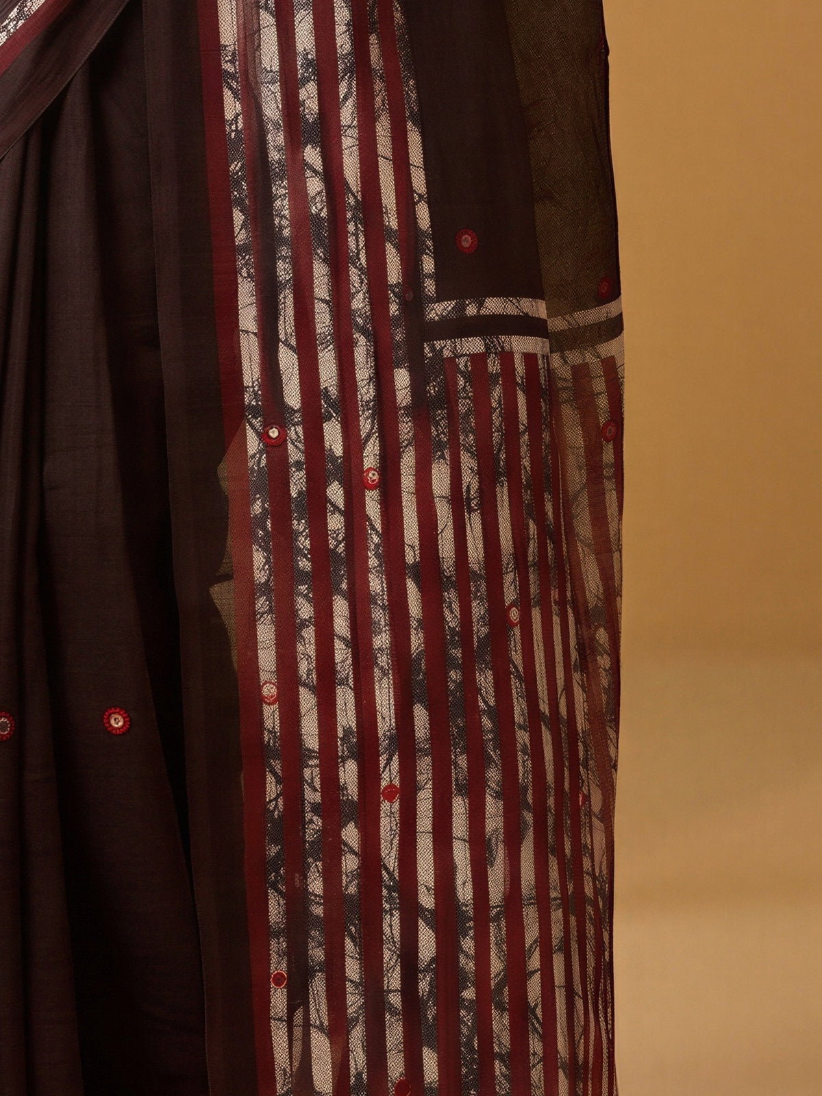 Pallu detail of dark brown linen saree showing batik wax-resist design and solid border
