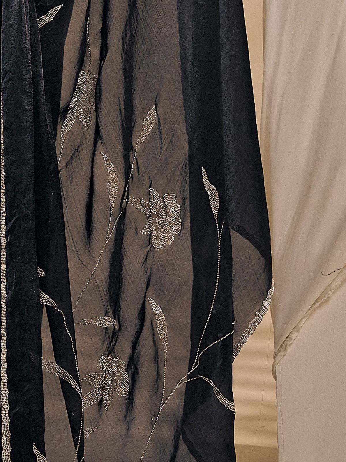 Pallu detail of black satin silk saree showing ornamented surface design and embellished border