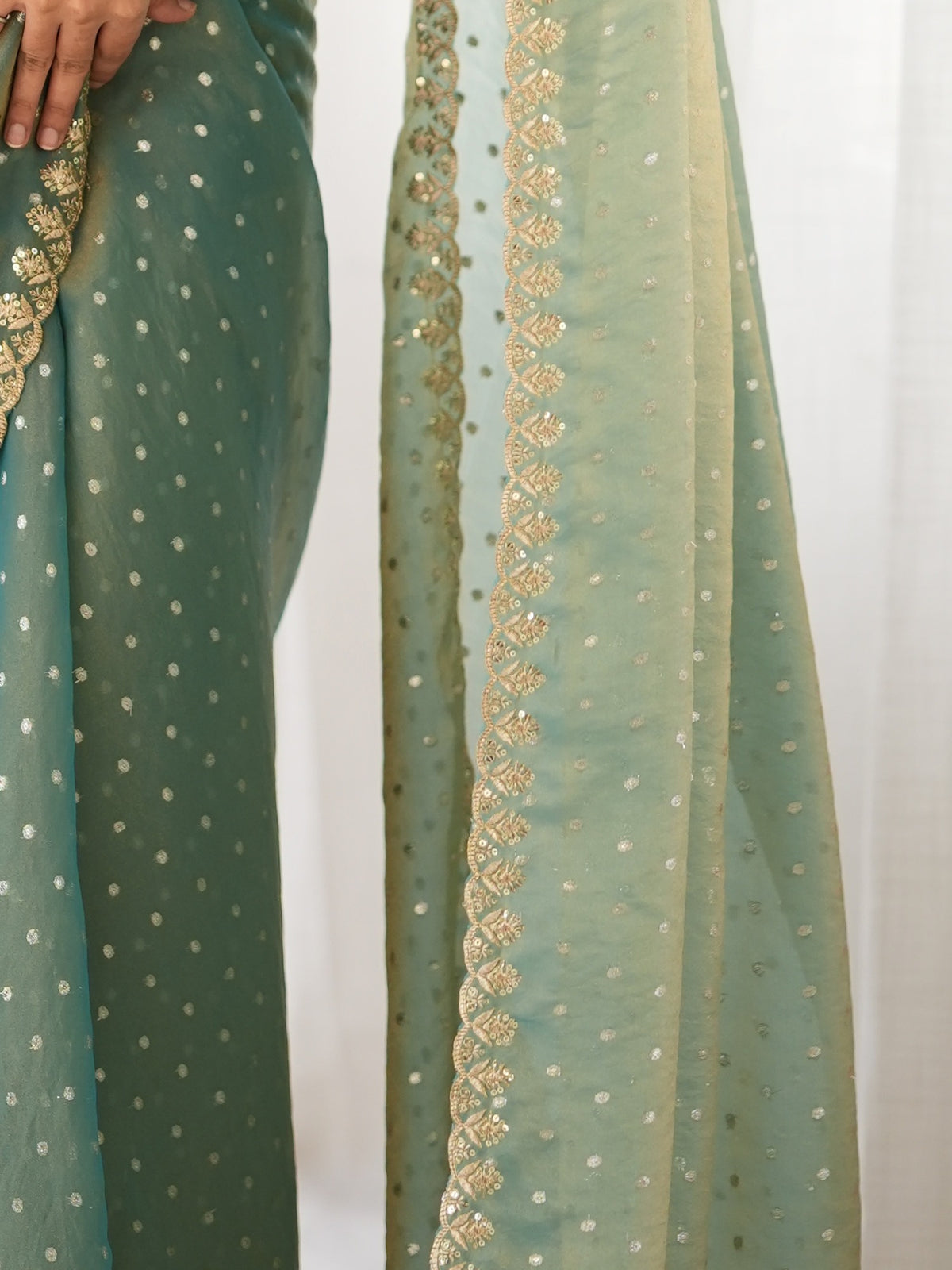 Pallu detail of light blue georgette saree showing zari butta (metallic motif) work and embellished border