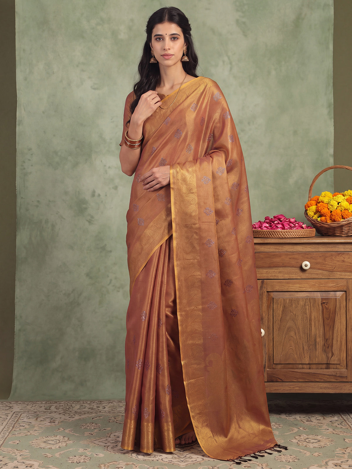 Woman wearing copper linen saree with traditional indian motif work and copper blouse