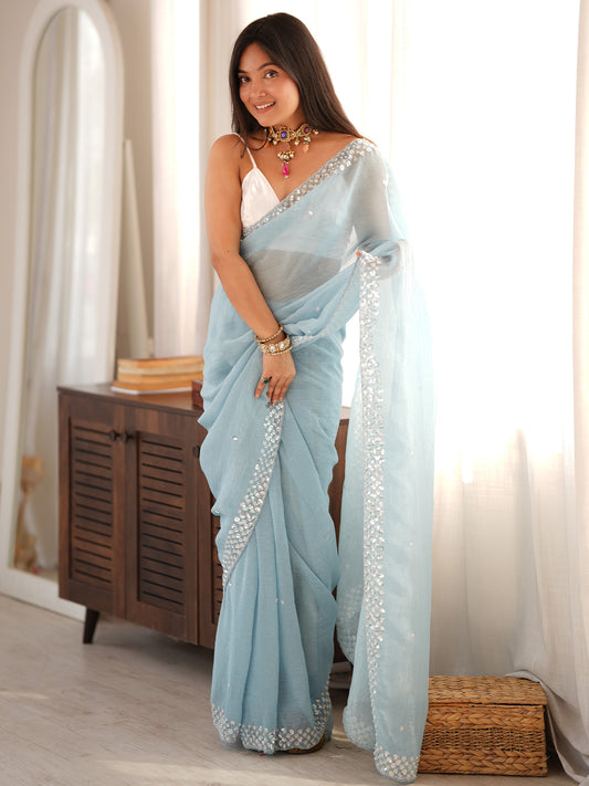 Woman wearing light blue georgette saree with embroidered motif work and white blouse