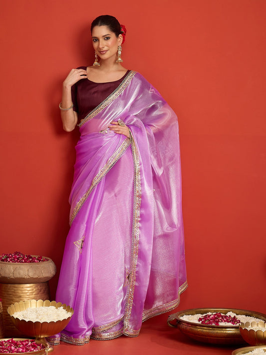 Woman wearing lavender paper silk saree with ornamented surface design and maroon blouse