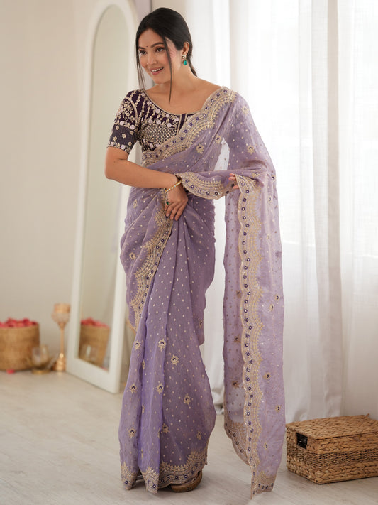 Woman wearing lavender silk blend saree with ornamented surface design and purple blouse