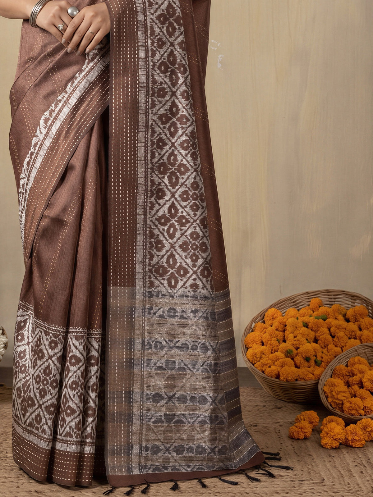 Pallu detail of brown silk cotton saree showing ikat resist-dyed pattern and embroidered border