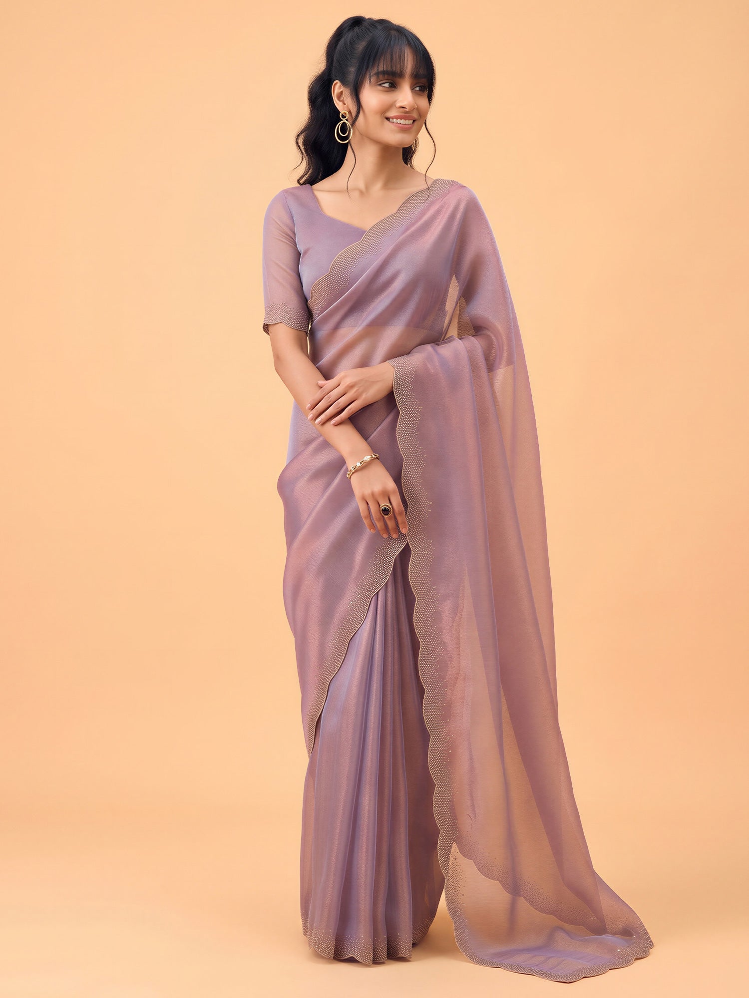 Woman wearing metallic satin silk saree with ornamented surface design and metallic blouse