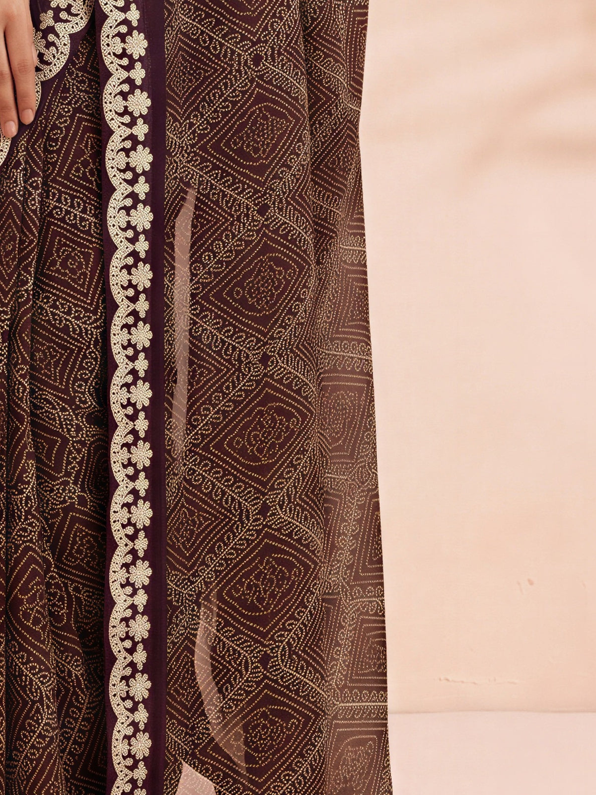 Pallu detail of wine georgette saree showing bandhani tie-dye dot work and embellished border
