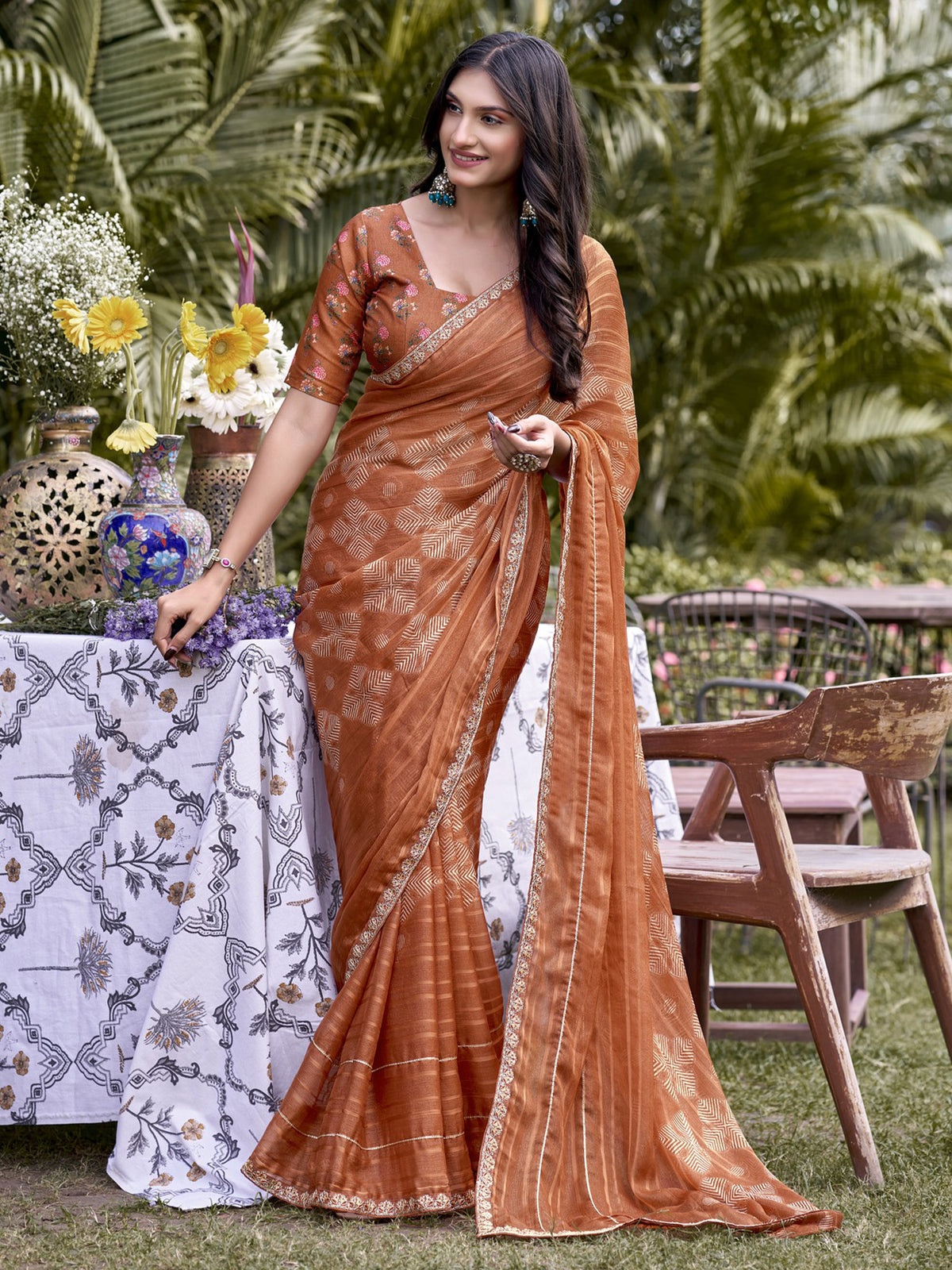 Woman wearing rust chiffon saree with traditional indian motif work and rust blouse