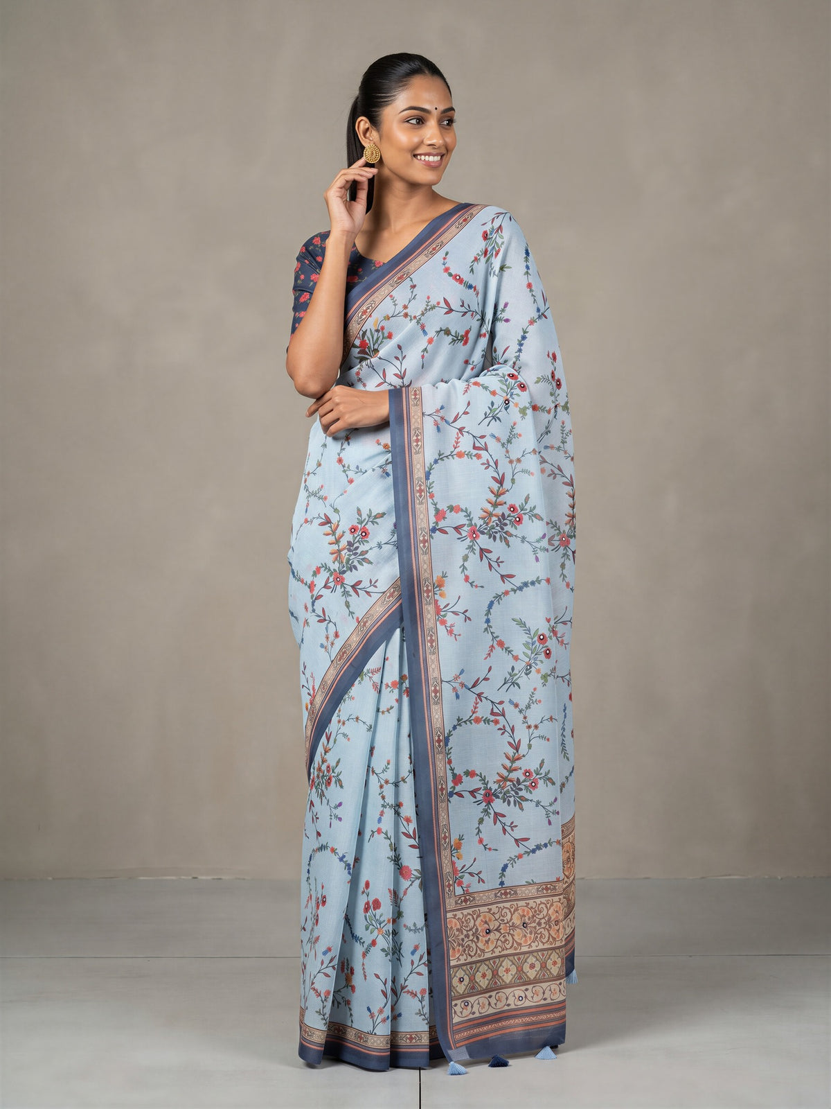 Woman wearing light blue linen blend saree with botanical floral and leaf design and navy blue blouse