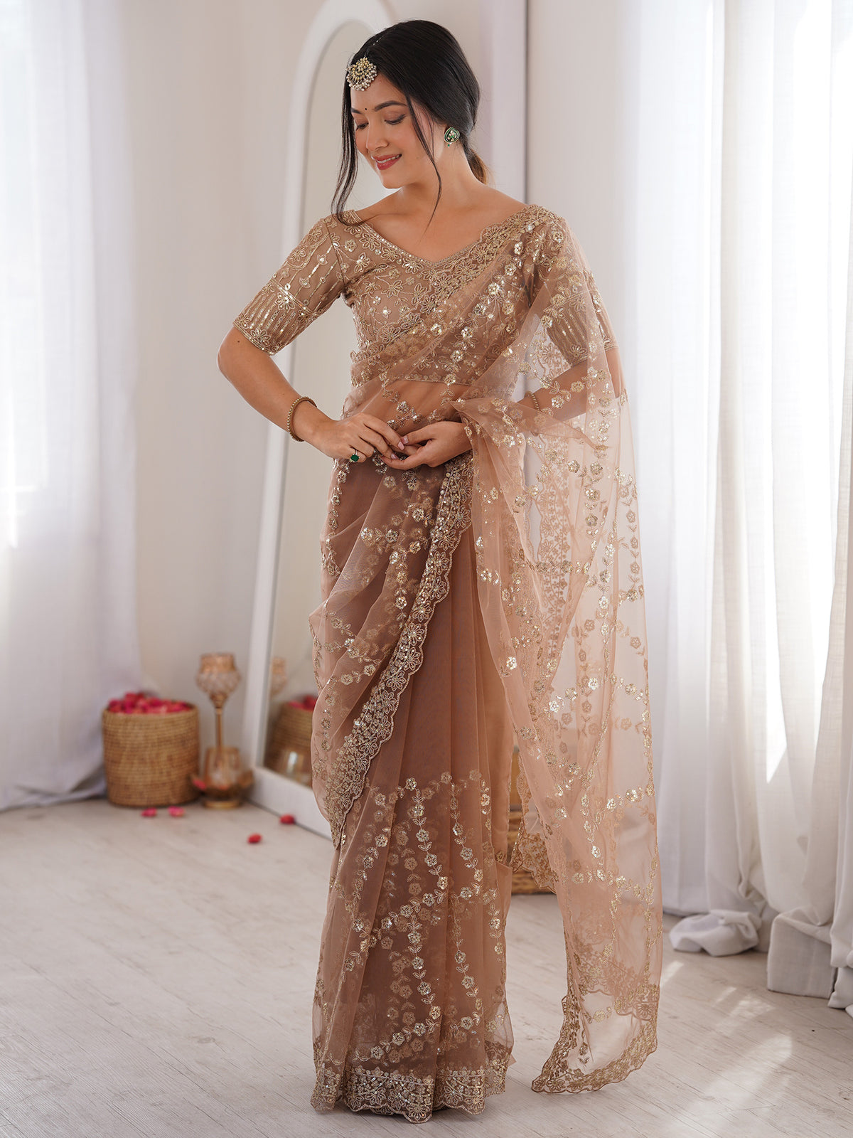 Woman wearing beige net saree with ornamented surface design and beige blouse
