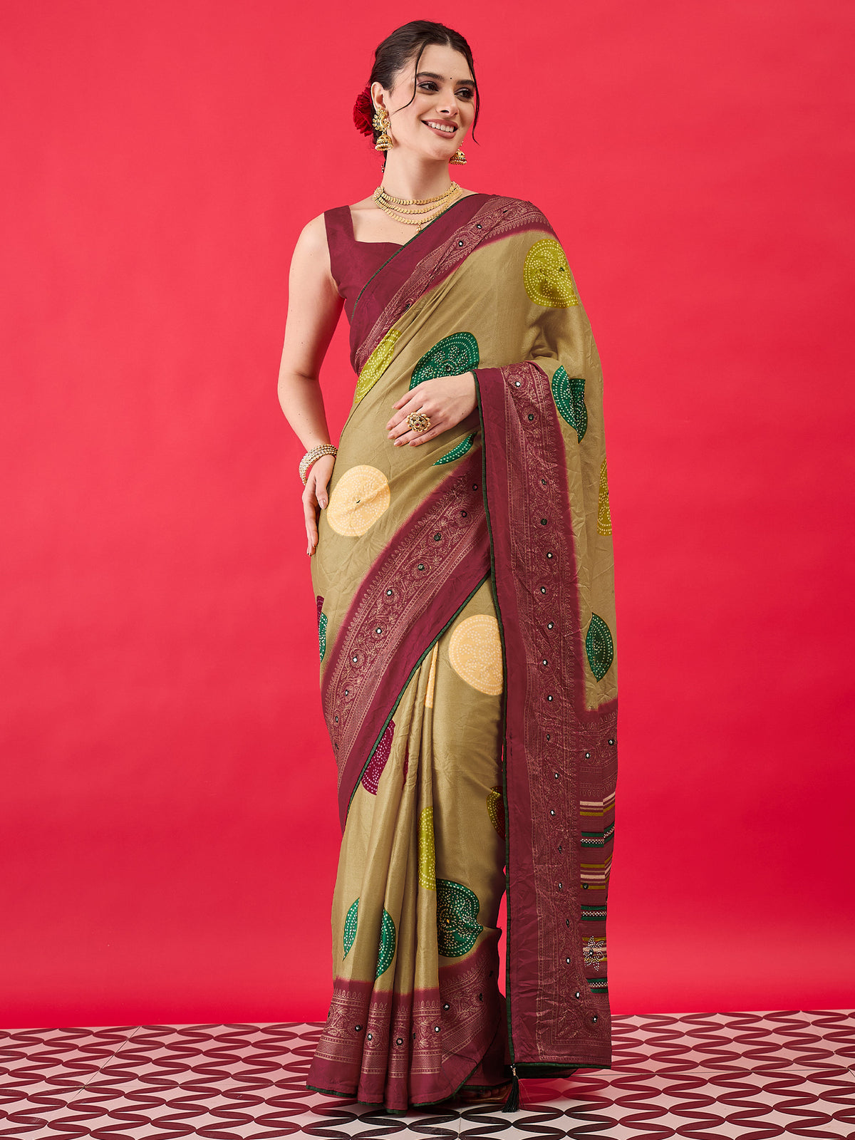 Woman wearing gold georgette saree with bandhani tie-dye dot work and maroon blouse