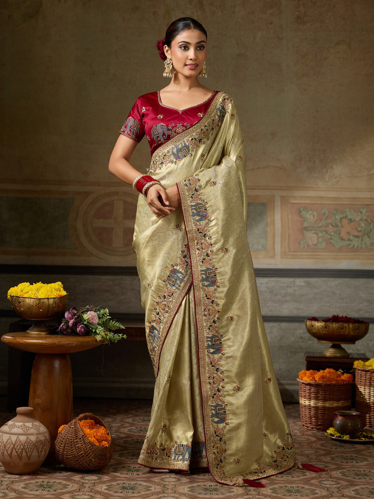 Woman wearing gold silk blend saree with ornamented surface design and maroon blouse