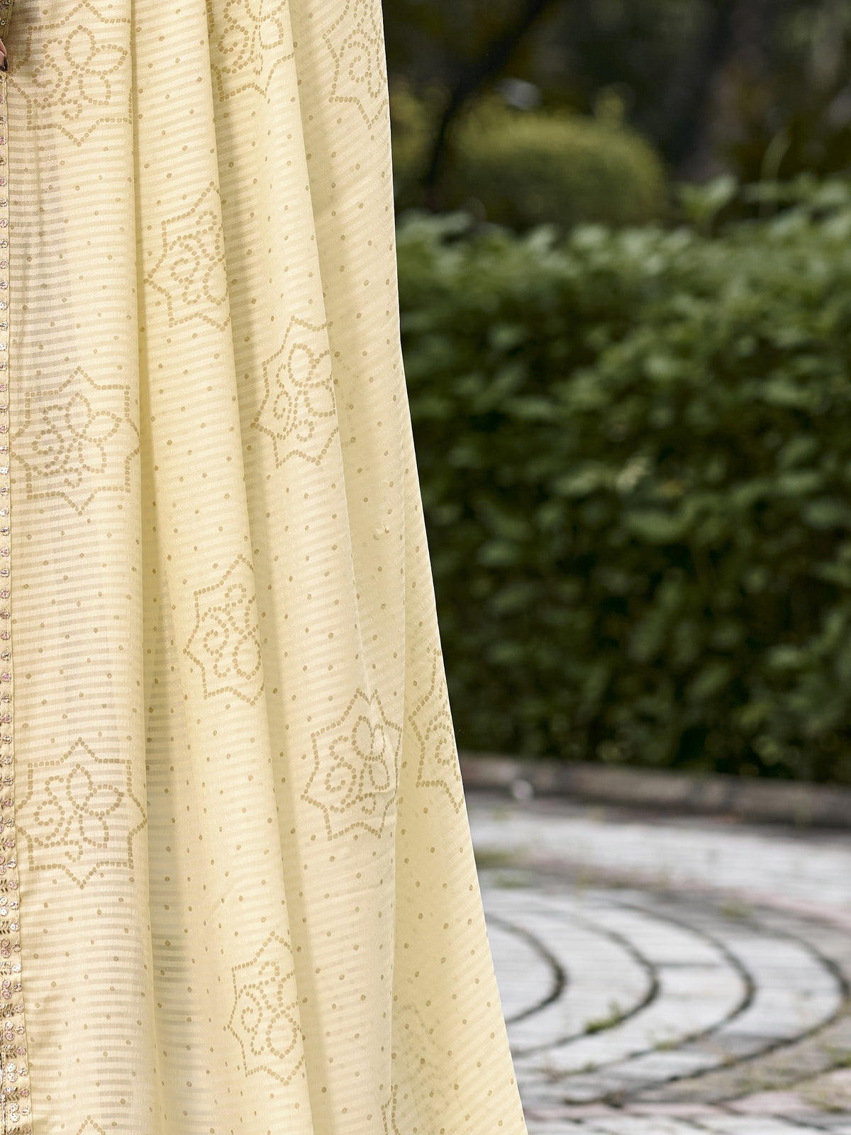 Pallu detail of cream georgette saree showing bandhani tie-dye dot work and zari border
