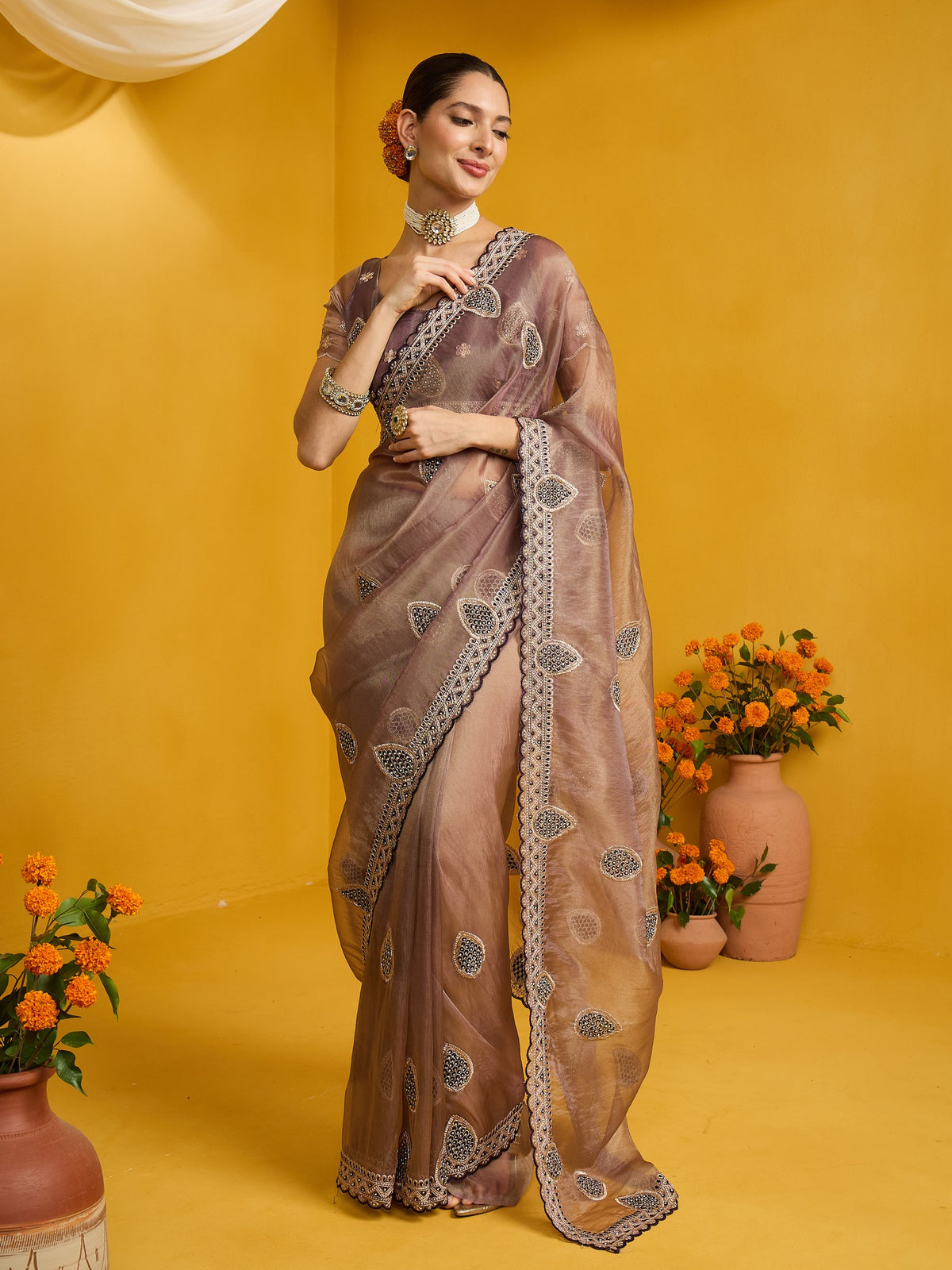 Woman wearing rose gold organza saree with ornamented surface design and rose gold blouse
