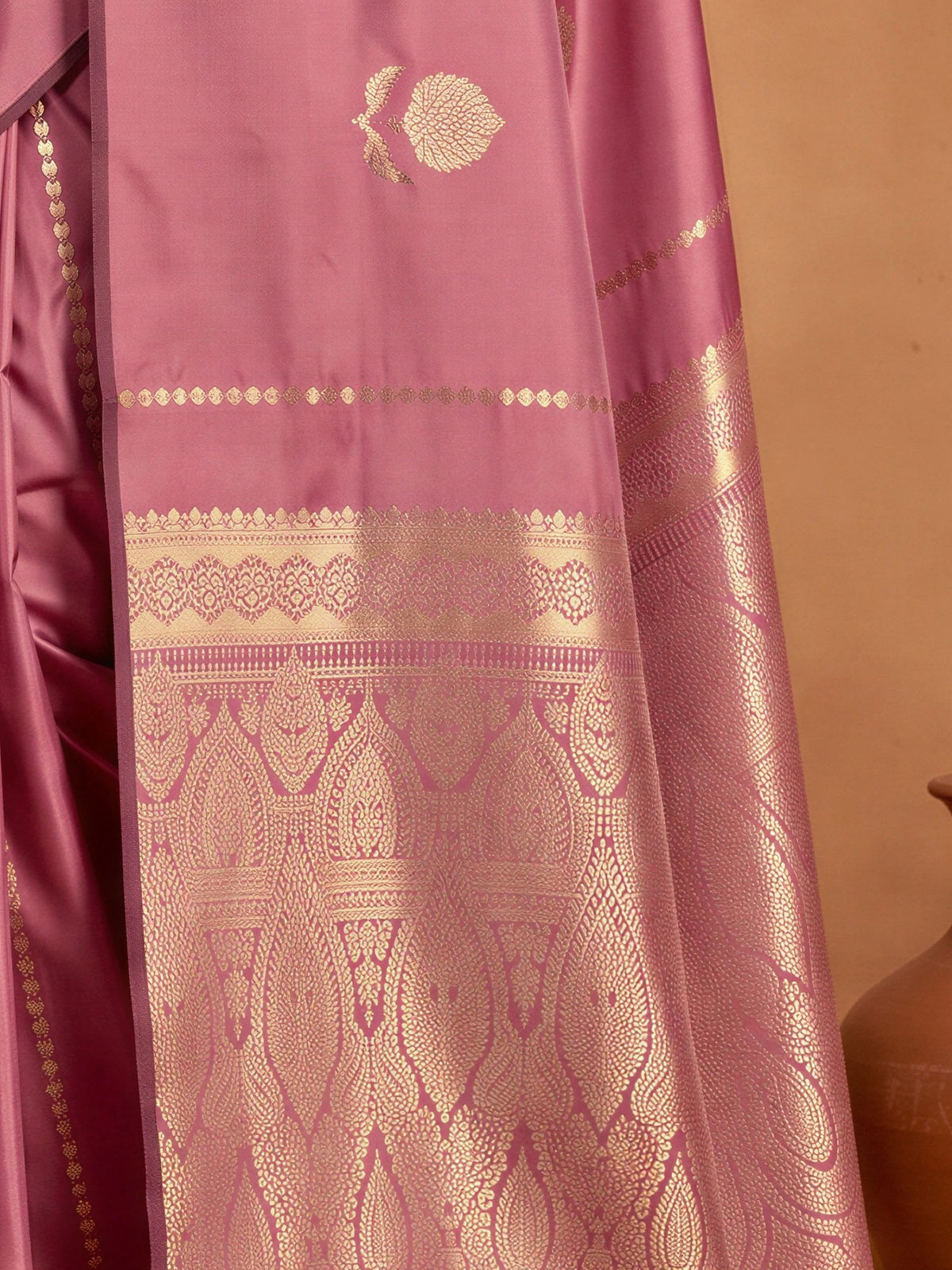 Pallu detail of mauve satin silk saree showing traditional indian motif work and no border border