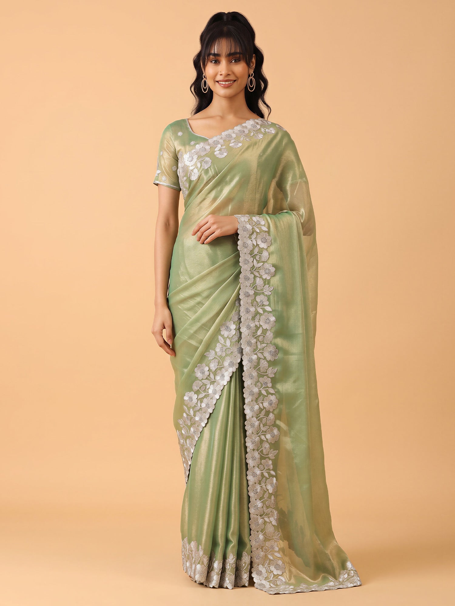 Woman wearing light green chiffon saree with ornamented surface design and light green blouse