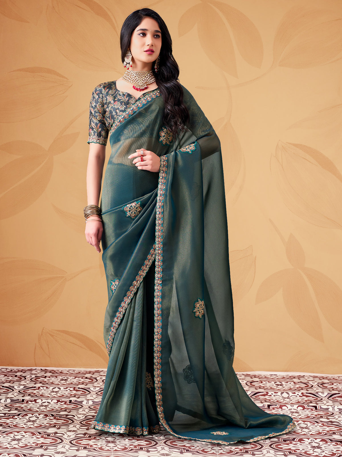 Woman wearing teal blue tissue saree with ornamented surface design and teal blue blouse