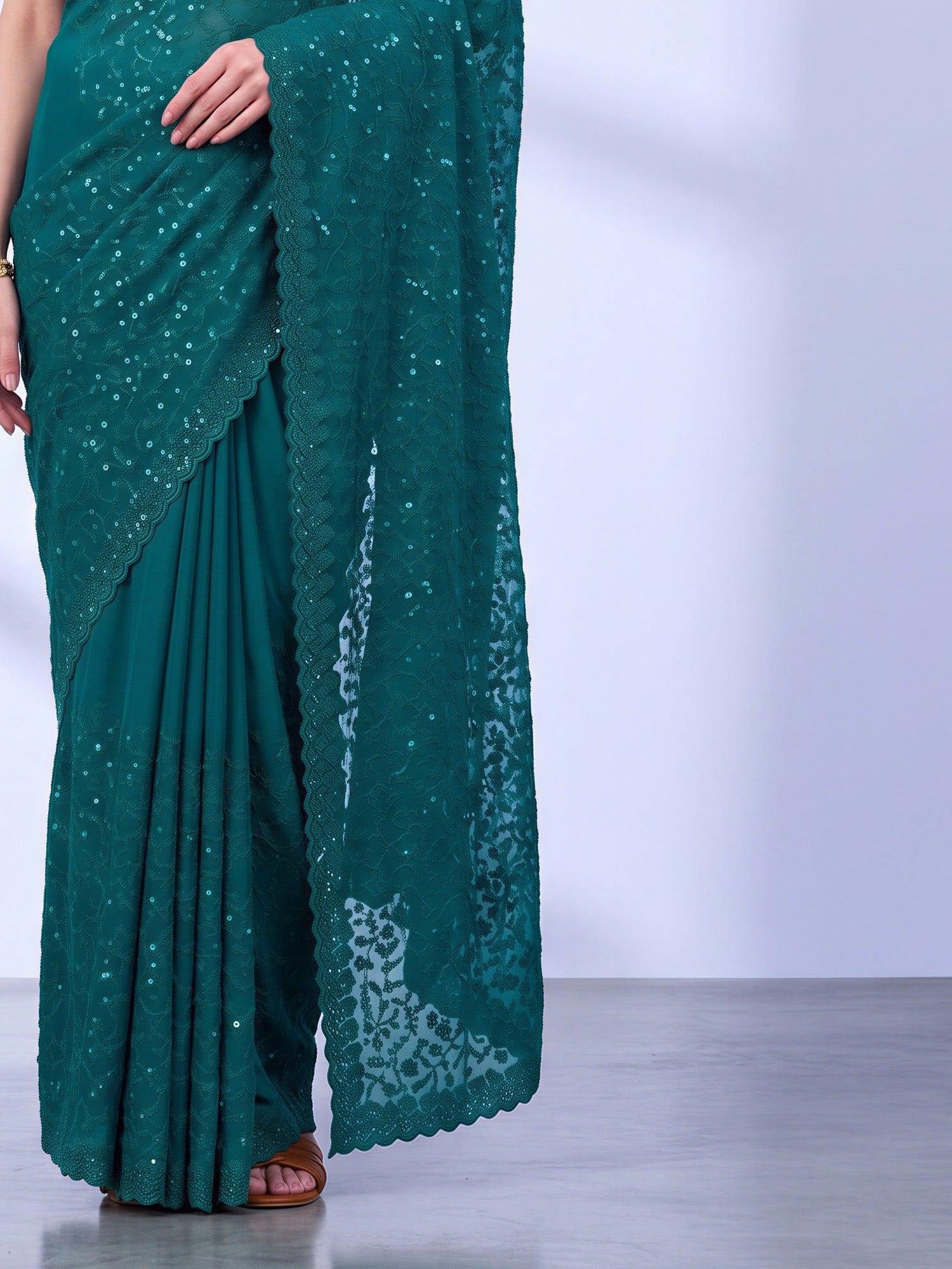Pallu detail of teal green tissue saree showing ornamented surface design and embellished border
