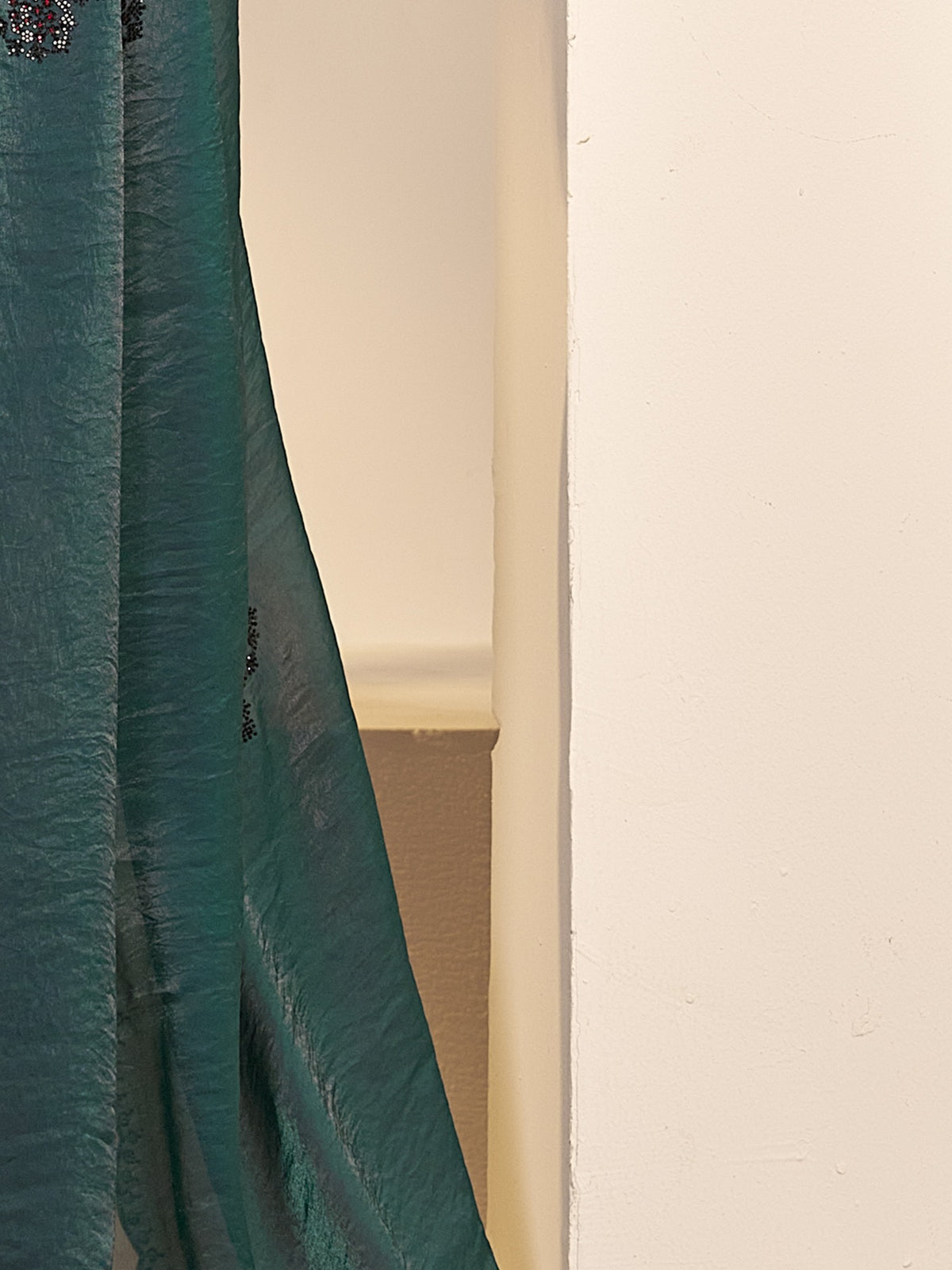 Pallu detail of teal green satin silk saree showing ornamented surface design and embellished border
