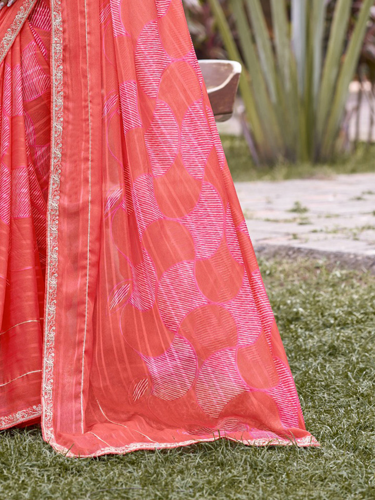 Pallu detail of coral chiffon saree showing traditional indian motif work and embellished border