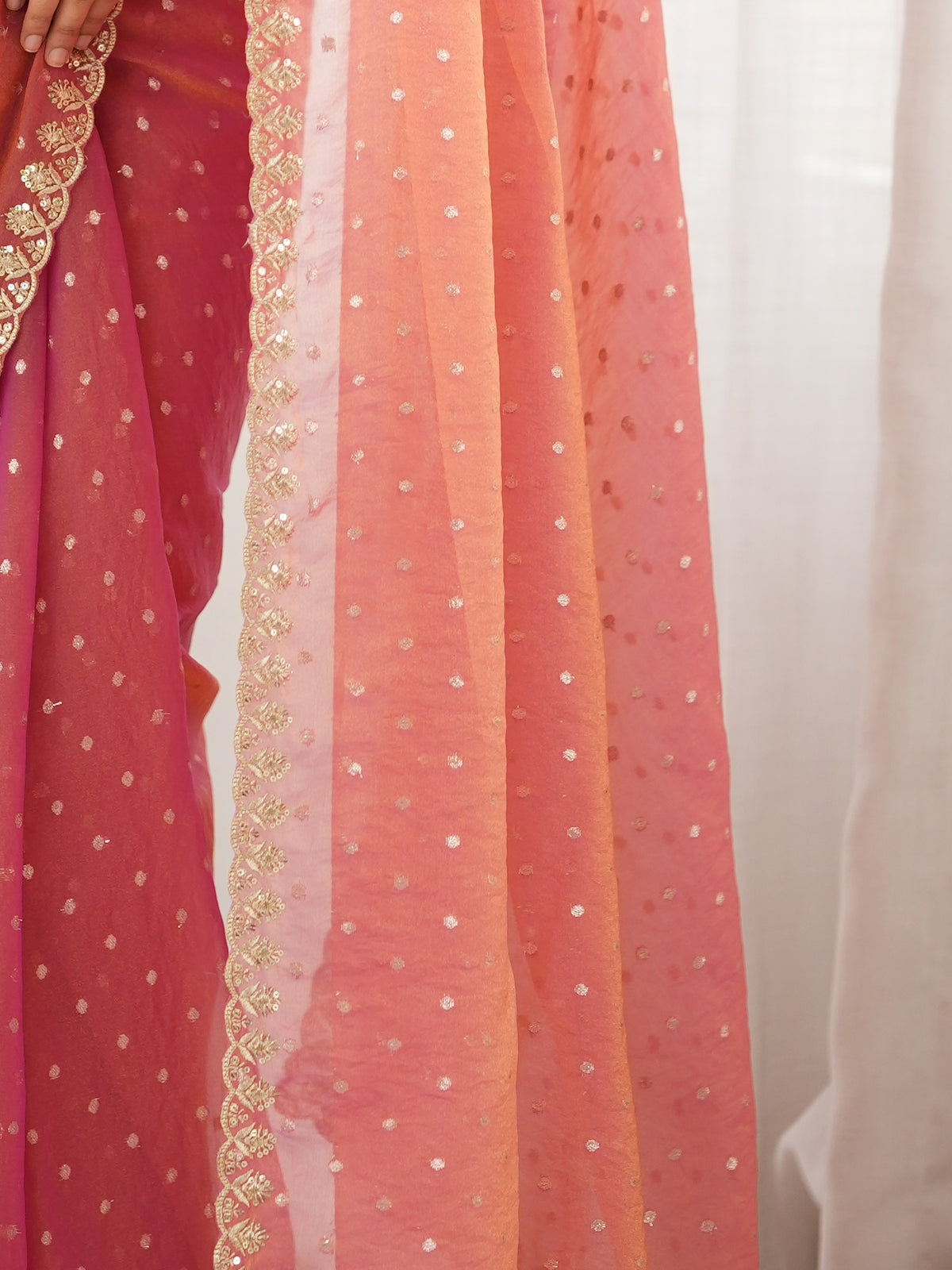 Pallu detail of pink georgette saree showing zari butta (metallic motif) work and embellished border