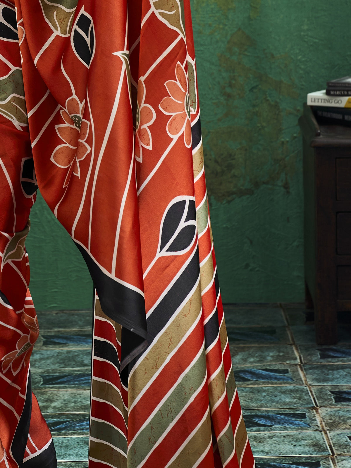 Pallu detail of orange satin saree showing all-over floral design and printed border