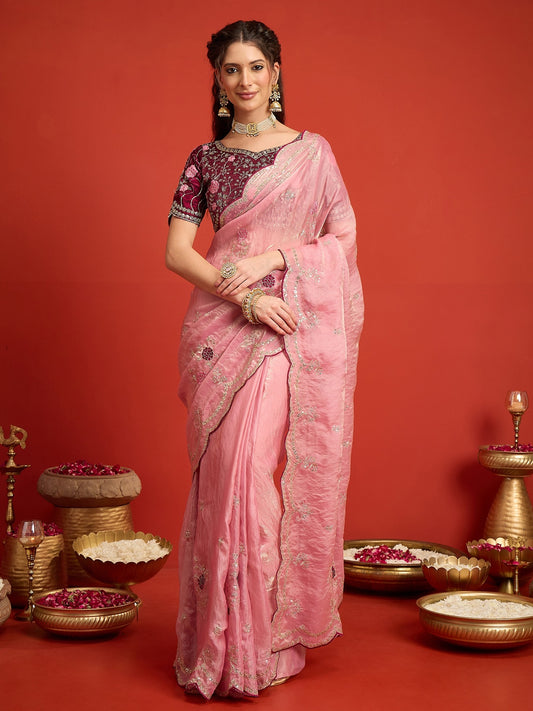 Woman wearing pink satin silk saree with ornamented surface design and maroon blouse