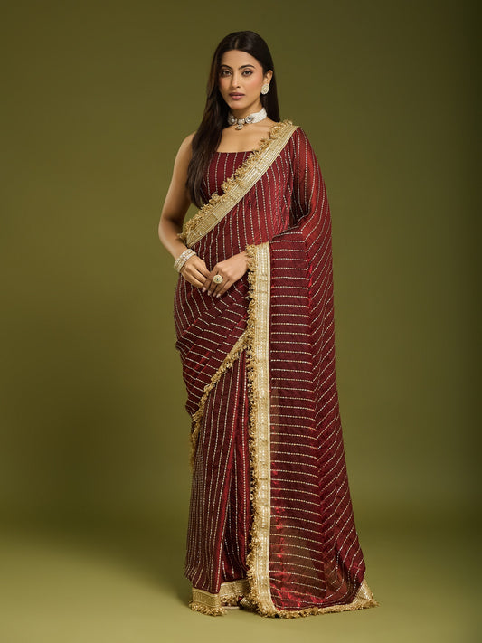 Woman wearing maroon satin saree with ornamented surface design and maroon blouse