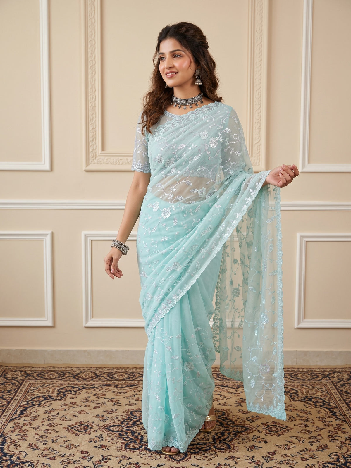 Woman wearing light blue georgette saree with ornamented surface design and light blue blouse