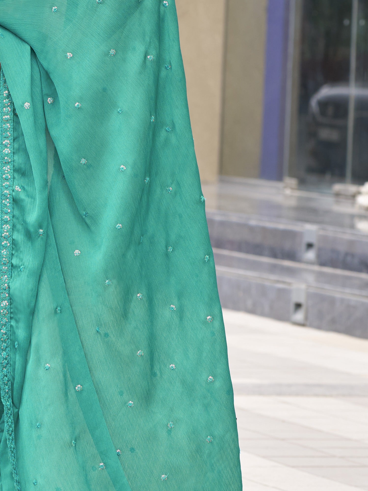 Pallu detail of teal green satin silk saree showing ornamented surface design and embellished border