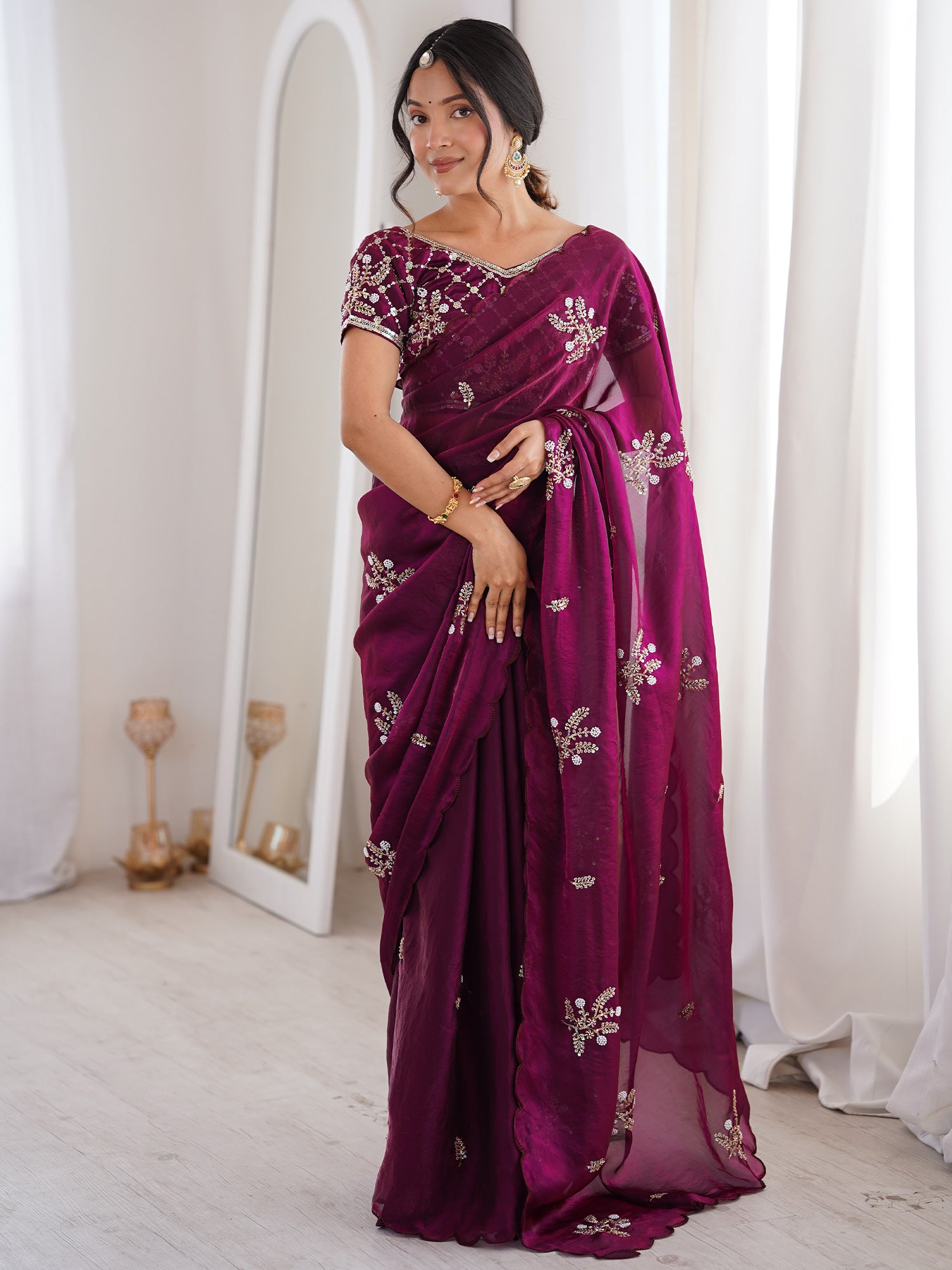 Woman wearing purple satin saree with ornamented surface design and purple blouse