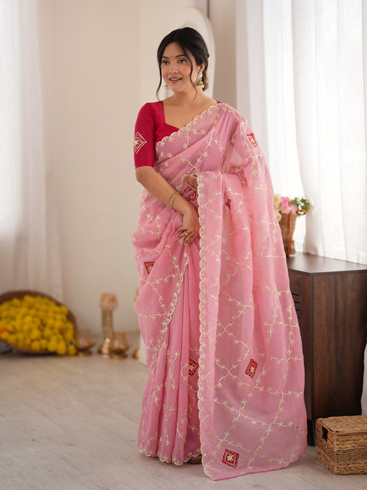 Woman wearing pink paper silk saree with ornamented surface design and pink blouse