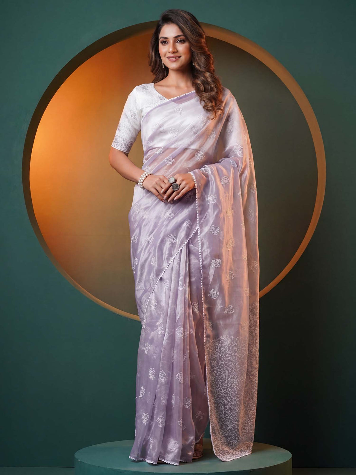 Woman wearing lavender organza saree with embroidered motif work and white blouse