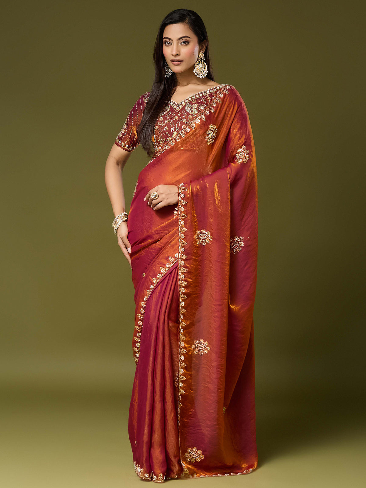 Woman wearing orange satin silk saree with ornamented surface design and orange blouse