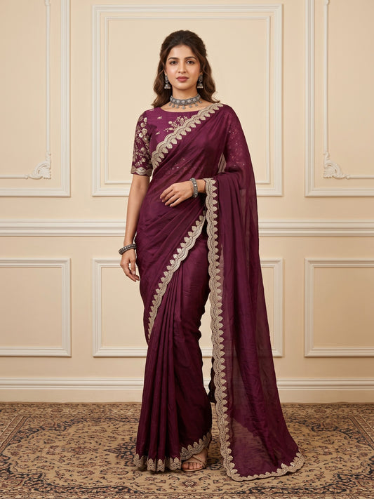 Woman wearing burgundy tissue saree with ornamented surface design and burgundy blouse