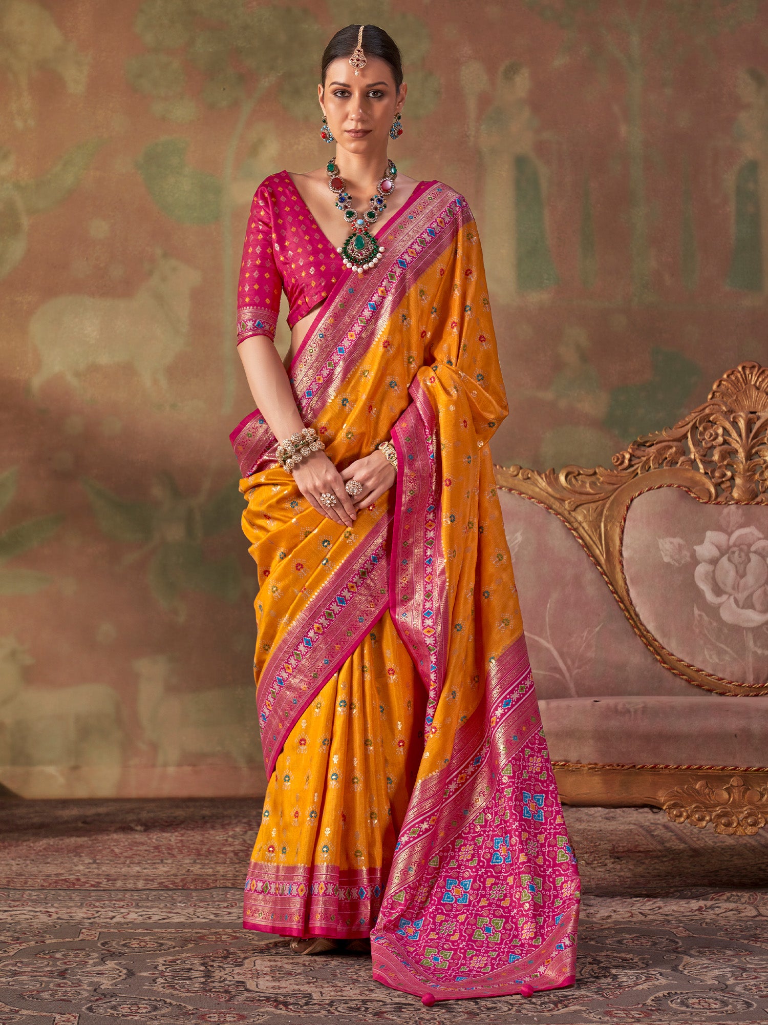 Woman wearing mustard silk blend saree with traditional indian motif work and pink blouse